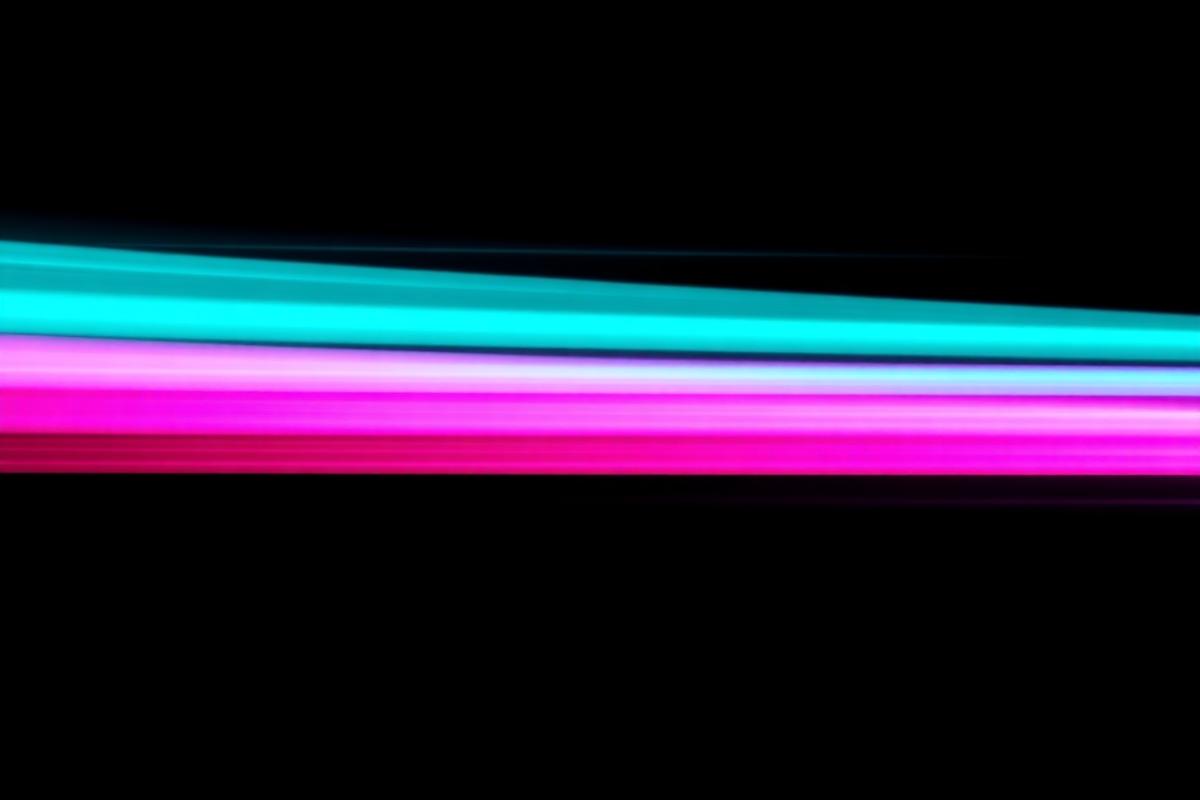 Neon teal and magenta light streaks racing across a black background